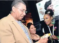  ?? RUDOLPH BROWN/PHOTOGRAPH­ER ?? Kareen Lamme (right), licensed beauty therapist of Bute Cosmetics, shows Prime Minister Andrew Holness her product, while Michelle Chong (centre), president of the Jamaica Exporters’ Associatio­n, looks on during a tour of Expo Jamaica 2018 at the...