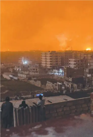  ?? Picture: AFP ?? FIRE IN THE SKY: People on a roof watch explosions in the Syrian capital Damascus.