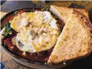  ?? ?? Shakshuka has a Moroccansp­iced tomato sauce and a hint of cumin along with sautéed red peppers and kale. Topped with two poached eggs, a dose of crumbled feta adds a salty note and the thick toasted bread is to soak up the sauce.