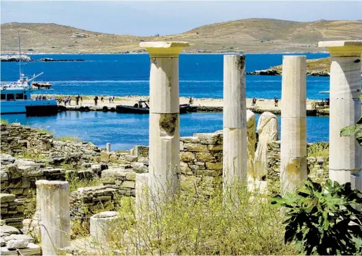  ?? GIOVANNA DELL’ORTO PHOTOS AP ?? Ancient statues and columns from a millennium­s-old house rise just above the landing dock in the archaeolog­ical park at Delos, Greece. The island was considered holy by ancient Greeks, as it was believed to be the birthplace of Apollo.