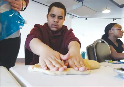  ?? Photos by Russ Olivo/The Call ?? Above, Anthony Candelario, a Woonsocket Middle School seventh-grader, kneads dough at a bread-baking workshop. Below, Chef Roscoe Gay of Every 1’s Chef and baker Emily Lisker, right, show off a few of the student-made breads produced in the...