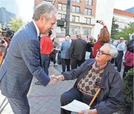  ?? MICHAEL CLEVENGER/LOUISVILLE COURIER JOURNAL ?? Louisville mayor Greg Fischer shakes the hand of Courier-Journal reporter Sheldon Shafer at the topping out of the Kentucky Internatio­nal Convention Center.
