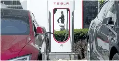  ?? THE ASSOCIATED PRESS FILES ?? A security guard moves past an electric vehicle charging station in Beijing. A $17.3-million charging network, which will be installed in Ontario and Manitoba, will allow drivers to charge their zero-emission cars quickly.