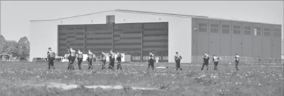  ?? RECORD FILE PHOTO ?? In this 2013 file photo, Hamilton police officers search the property in front of the Millardair hangar at the Waterloo Region airport. The hangar was built with help from a large bank loan.