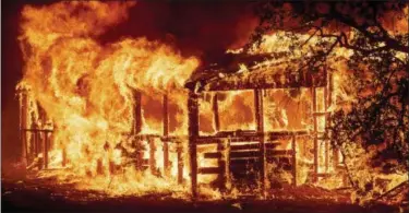  ?? NOAH BERGER — THE ASSOCIATED PRESS ?? A structure burns as the Carr Fire races along Highway 299near Redding on Thursday.