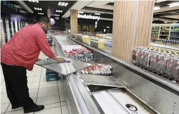  ?? PICTURE: SIMPHIWE MBOKAZI/AFRICAN NEWS AGENCY (ANA) ?? AFTERMATH: SuperSpar Rosettenvi­lle employee Phillip Monjane sanitises a fridge where cold meat products had been displayed.