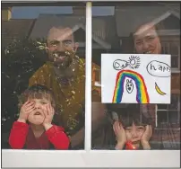  ?? (File Photo/AP/Elizabeth Dalziel) ?? Amelie and sister Camille look out their front window in April as the lockdown enters its third week along with their parents Victoria and Damian Kerr in Berkhamste­d, England.