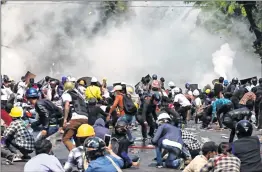  ?? —AFP ?? Protesters react after police fired tear gas during a agitation against the military coup in Mandalay.