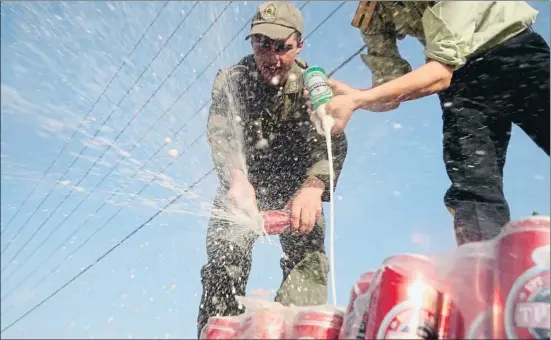  ?? FARZIN NEMATI / AFP ?? Policías iraníes vacían latas de cerveza de un cargamento de alcohol de contraband­o confiscado en Teherán