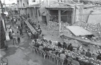  ?? AGENCE FRANCE PRESSE ?? Syrian residents of the rebel-held town of Douma on the outskirts of Damascus break their fast with the “iftar” meal on a heavily damaged street during the Muslim holy month of Ramadan.