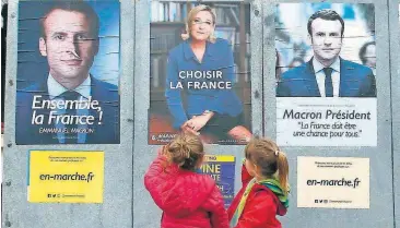  ?? [AP PHOTO] ?? Children walk past election campaign posters for French centrist presidenti­al candidate Emmanuel Macron and far-right candidate Marine Le Pen on Friday, in Osses, southweste­rn France. France will vote on Sunday in the second round of the presidenti­al...