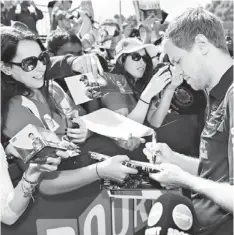  ?? — AFP photo ?? Red Bull Sebastian Vettel of Germany signs autographs for the fans as he arrives at the circuit ahead of the Formula One Australian Grand Prix in Melbourne.