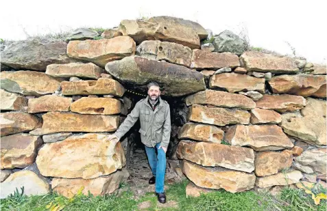  ??  ?? Tim Daw, a Wiltshire farmer, at the entrance of the long barrow tomb he built on his land. He says the business rates decision means worshipper­s will have to ‘pay to pray’