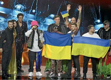  ?? GETTY IMAGES ?? Eurovision Song Contest hosts Alessandro Cattelan, left, Laura Pausini and Mika with Kalush Orchestra of Ukraine as the band is named winner during the Grand Final show of the 66th Eurovision Song Contest at Pala Alpitour in Turin, Italy. Band front man Oleh Psiuk made an impassione­d plea to free fighters still trapped beneath a sprawling steel plant in Mariupol. “Help Azovstal, right now,’’ Psiuk implored from beneath a bright bucket hat that has become the band’s trademark among fans.