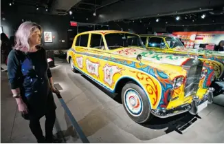  ?? RYAN REMIORZ/THE CANADIAN PRESS ?? Deborah Tucker, who was at the only Beatles performanc­e in Montreal in 1964, looks at John Lennon’s psychedeli­c Rolls-Royce at the Pointe-à-Callière museum.