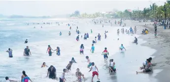  ??  ?? DESTINO. Los veraneante­s disfrutaro­n ayer de las olas en la playa municipal de Tela.