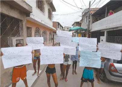  ??  ?? Moradores exibem cartazes com pedidos de justiça pela morte de rapaz, a tiros, durante incursão da PM