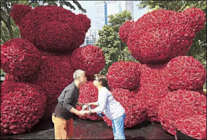  ?? EDD GUMBAN ?? With the approach of Valentine’s Day, a couple poses for photos with roses clustered in the shape of teddy bears at Bonifacio Global City in Taguig yesterday.