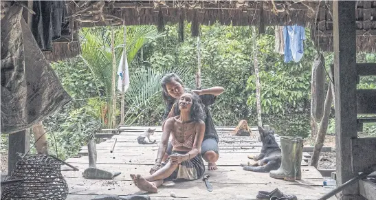  ??  ?? AT HOME: Silumang Sipelege, a Mentawai tribe member, and a relative at her Siberut Island house. The Mentawai arrived on the island around 2,000 years ago.