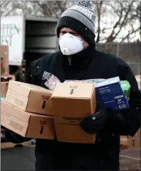  ?? PROJECT ISAIAH VIA AP ?? A Detroit Health Department worker helps to distribute packaged food as part of the Project Isaiah relief efforts bringing thousands of packaged meals to COVID-positive Detroit residents on Friday.