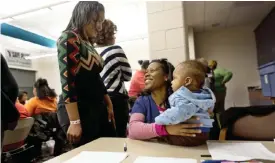  ??  ?? MILWAUKEE : Volunteer Monet Williams, center, holds a friend’s baby whose mother is participat­ing in a monthly gathering that promotes breast-feeding, as she talks to another volunteer at a YMCA. — AP photos