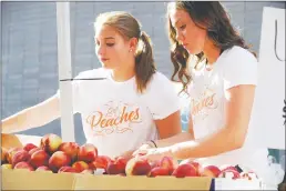  ??  ?? Chris Kaufman/appeal-democrat Alyssa Baggett, left, and Abby Pate stock peaches at the Sodaro Orchards stand at the Marysville Peach Festival in July 2018.