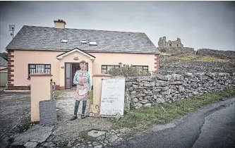  ?? ANDY HASLAM THE NEW YORK TIMES ?? Aine O’Graiofa outside her home and restaurant, with O’Brien’s Castle in the background, on Inisheer.
