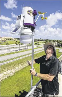  ?? PHOTOS BY LANNIS WATERS / THE PALM BEACH POST ?? Luke Hunnewell installs the solar-powered, wirelessly connected weather station Thursday atop the press box at Boynton Beach High School’s football stadium. The state-of-the-art weather station from WeatherSTE­M will allow Boynton High students to...