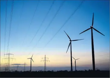  ?? Alexander Koerner Getty Images ?? WIND TECHNOLOGY attracted a record $99.5 billion last year from investors, up 11% from 2013. Above, power lines and wind turbines at dawn near a coal-fired power plant near Sehnde, Germany.