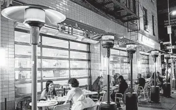  ?? JEENAH MOON/THE NEWYORK TIMES ?? Patrons dine outdoors under propane heaters last week at La Pecora Bianca, a restaurant in New York.
