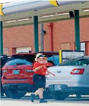  ?? [PHOTO BY DOUG HOKE, THE OKLAHOMAN] ?? A Sonic car hop walks behind a row of cars at the drive-in at 900 W Sheridan during lunch Wednesday.