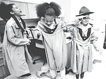  ?? PHOTOS BY SHELLEY MAYS/THE TENNESSEAN ?? Above: Girl Scouts Troop 6000 members Hailey Johnson, left, Hannah Johnson and Nevaeh Motley try on vintage replica Girl Scouts uniforms Dec. 9 during a visit to the Girl Scouts of Middle Tennessee headquarte­rs in Nashville. In August 2017, Girl Scouts...