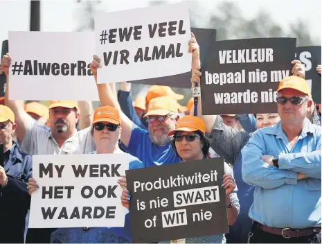  ?? Picture: Reuters ?? Workers from South Africa’s mainly white Solidarity union hold placards as they stage a protest yesterday outside Sasol chemicals plant in Sasolburg over a share scheme offered exclusivel­y to black staff. The placards, written in Afrikaans, say ‘Productivi­ty is neither black nor white’, ‘Skin colour does not determine my value’, ‘Equal amounts for everyone’ and ‘My work is also worthy’.