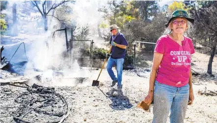  ?? SARAH REINGEWIRT­Z AP ?? Cheryl Poindexter returns to her property on Monday after the Bobcat fire burned her home of 27 years and the 11-acre property where she ran an animal rescue in Juniper Hills. Her friend Dale Burton attends to remaining hot spots.