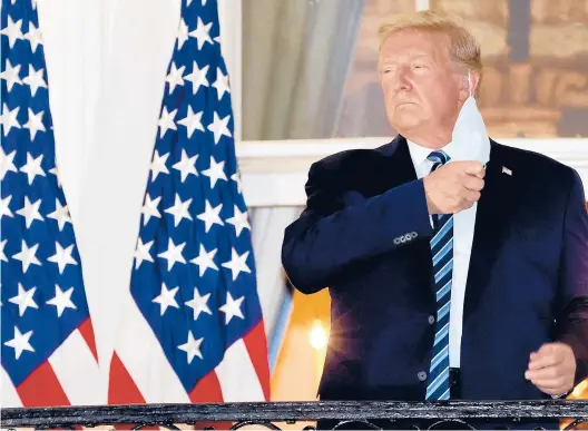  ?? WIN MCNAMEE/GETTY ?? President Donald Trump removes his mask on the White House balcony Oct. 5 upon his return from Walter Reed National Military Medical Center. Trump spent three days hospitaliz­ed for the coronaviru­s.