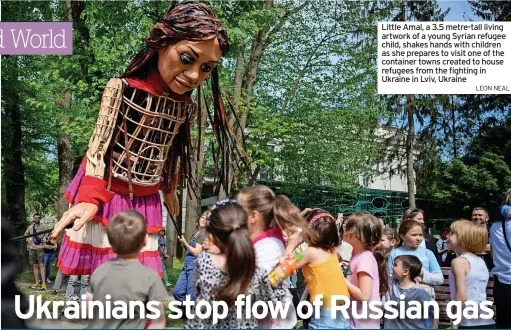  ?? LEON NEAL ?? Little Amal, a 3.5 metre-tall living artwork of a young Syrian refugee child, shakes hands with children as she prepares to visit one of the container towns created to house refugees from the fighting in Ukraine in Lviv, Ukraine