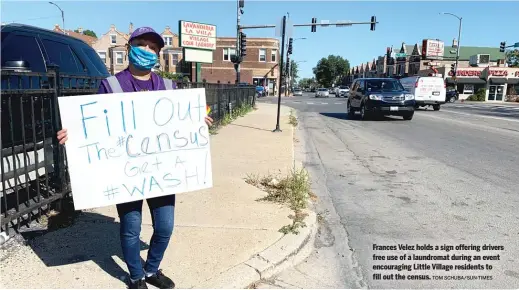  ?? TOM SCHUBA/SUN-TIMES ?? Frances Velez holds a sign offering drivers free use of a laundromat during an event encouragin­g Little Village residents to fill out the census.