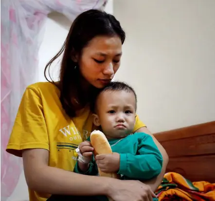  ??  ?? GRIEF: Left, Hoang Thi Thuong, wife of Nguyen Dinh Tu, a suspected victim of the tragedy, holds her son at their home in Nghe An province, Vietnam; Above and right, relatives of Anna Bui Thi Nhung listen to the latest news of their missing family member.