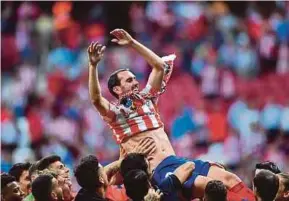  ?? AFP PIC ?? Atletico Madrid’s captain Diego Godin is given a grand send-off by teammates after the match against Sevilla on Sunday. Godin leaves the club after nine years.