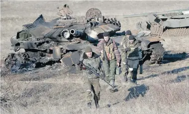  ?? VADIM GHIRDA/The Associated Press ?? Russia-backed separatist­s finish searching destroyed Ukrainian army tanks for functional weapons and ammunition near
the village of Lohvynove, outside Debaltseve, Ukraine, Sunday, on the edge of the territory under their control.