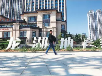  ?? CHEN JUNMIN / FOR CHINA DAILY ?? A man walks past Longfor Properties’ high-end living community in Dalian, Liaoning province.