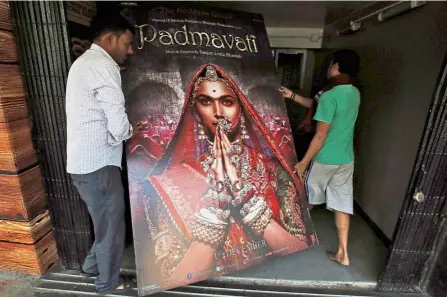  ??  ?? Controvers­ial epic: Workers carrying a poster advertisin­g upcoming Bollywood film ‘Padmavati’ towards a ticketing counter in a cinema hall in Kolkata, India. — Reuters