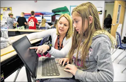  ?? BRANT SANDERLIN / BSANDERLIN@AJC.COM ?? Chestatee Elementary School teacher Joy Hall helps fourth-grader Raine Wilson with a writing assignment during class. The Forsyth County school has issued laptops, paid for by local philanthro­pists and community leaders, to students who meet certain...