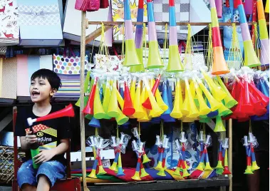  ??  ?? A CHILD makes noise with his plastic party horn to get the attention of customers at a sidewalk stall along Ilustre Street. BING GONZALES