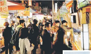  ??  ?? Tourist stroll through a food stall at Raohe street Night Market in Taipei,Taiwan. — Reuters photo