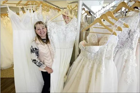  ?? JENNY SPARKS — LOVELAND REPORTER-HERALD ?? Tatyana Coleman, owner of Tatyana’s 5Star Dry Cleaners & Alteration­s, poses for a photo Friday, near some of the wedding dresses made in Ukraine for sale at her shop in Loveland.