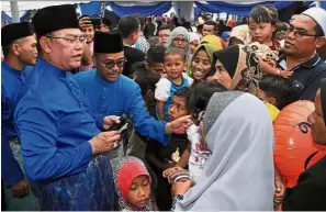  ??  ?? Festive occasion: Noh (left) distributi­ng ‘duit Raya’ to his constituen­ts at the Tanjong Karang open house at Dataran Tanjong Karang. — Bernama