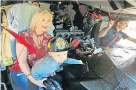  ?? RED HUBER/STAFF PHOTOGRAPH­ER ?? Aidan Rawls, 4, being held by his mother Elena of Apopka, blows the siren as he goes for a ride in a fire engine driven by Engineer Brian Hollins of the Lake Mary Fire Department.