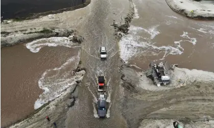  ?? Photograph: David Swanson/Reuters ?? Vehicles pass next to a break in a levee as floodwater­s inundate roads after days of heavy rain in Alpaugh, California, on 30 March.