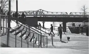  ??  ?? People walk along the Mississipp­i River at Tom Lee Park on a warm Sunday afternoon. JOE RONDONE / THE COMMERCIAL APPEAL